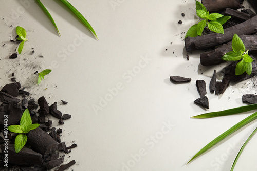 Flatlay of bamboo activated charcoal and charcoal powder decorate with green leaf in white background  photo