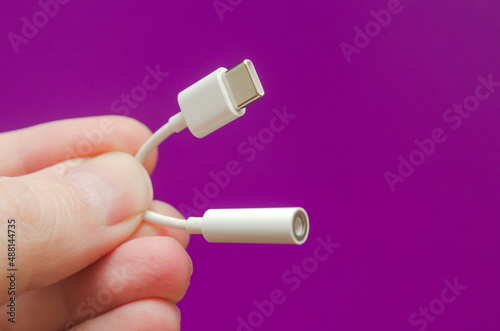 white adapter cable type-c to audio 3.5 in hand on a purple background