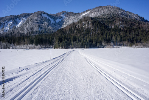empty cross country ski slope with mountains and no people with blue sky on a sunny day