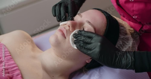 Cosmetologist cleans a woman's face with sponges, face care at the beauty salon, 4k 60p Prores HQ photo