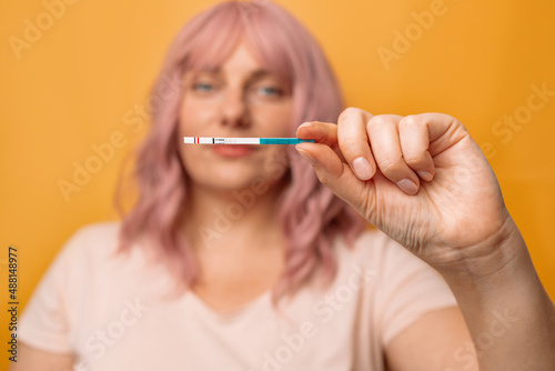 Happy young 30s woman holds a positive pregnancy test in her hand, pregnancy, women's health.