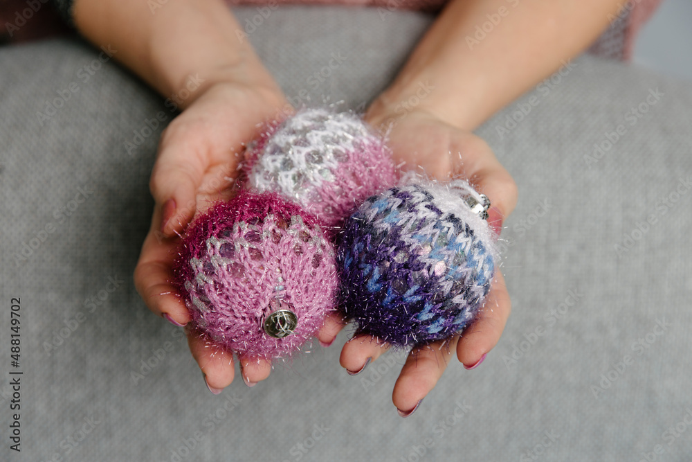 Christmas balls made of knitted threads in the hands of a girl, knitted Christmas toys