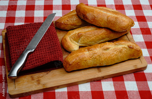 Homemade bread red checkered tablecloth cutting board and knife photo