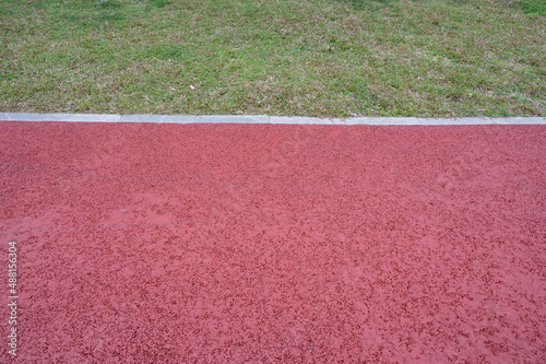 A short runway with green grass and red asphalt