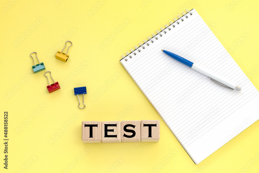 Notepad and pen on the background. Wooden cubes with word test. Notepad and pen on the background. Wooden cubes with word test.