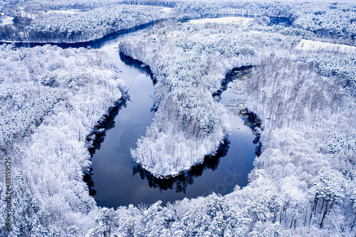 Winter winding river and snowy forest. Aerial view of Poland