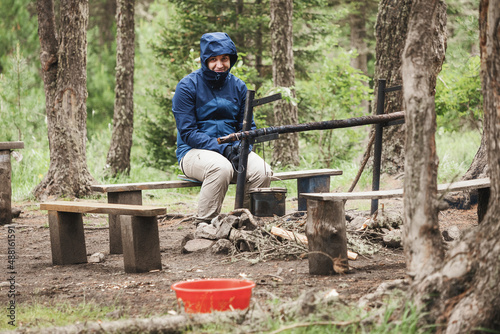 Man in a camping funny sitting near a place for a fire and freezes