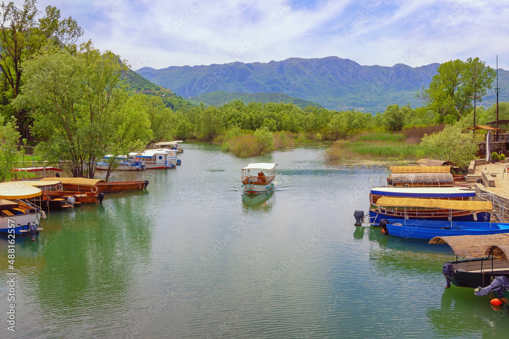  Montenegro. National Park Lake Skadar, Virpazar village. Beautiful mountain landscape with tourist boats on river