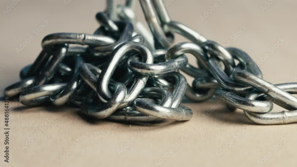 Metal iron chain slowly falls on a wooden table