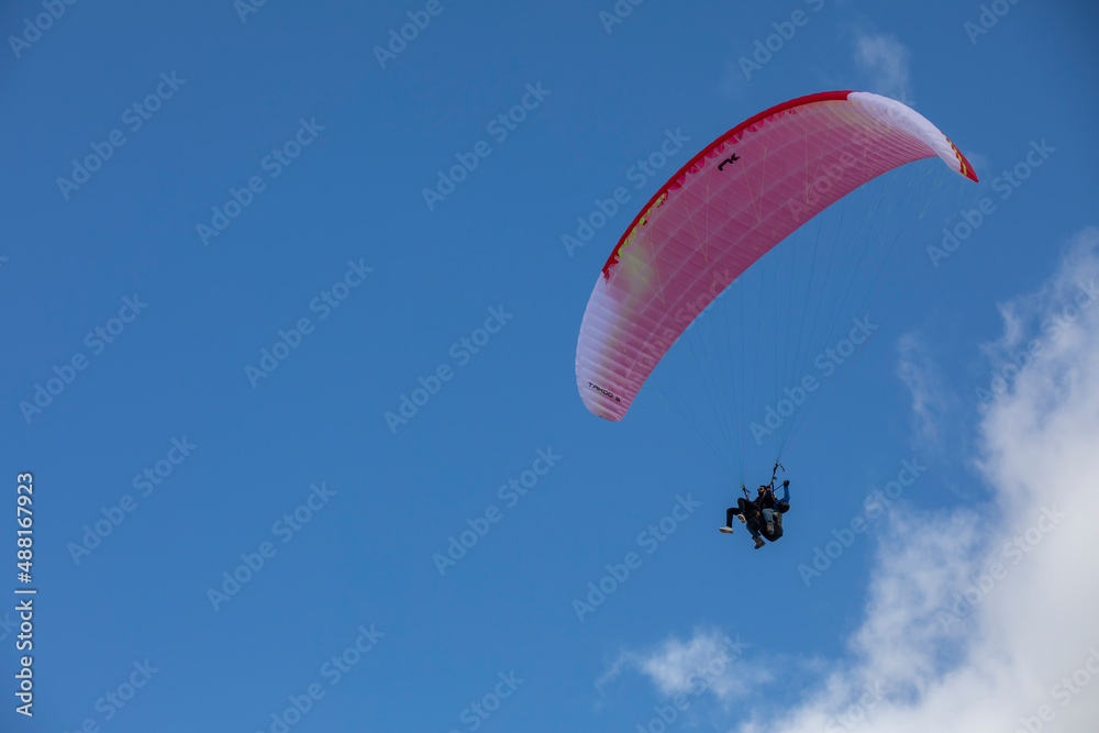 Paragliders in bright blue sky, tandem of instructor and beginner Paragliders in bright blue sky, tandem of instructor and beginner