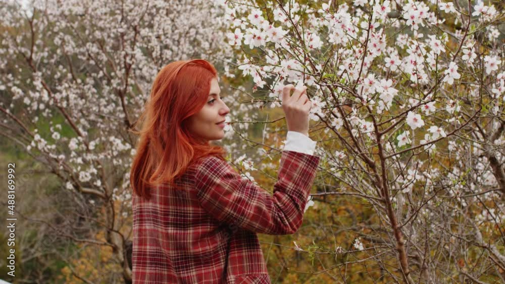 Happy red-haired girl under spring flower tree. Spring mood. Happy red-haired girl under spring flower tree. Spring mood.