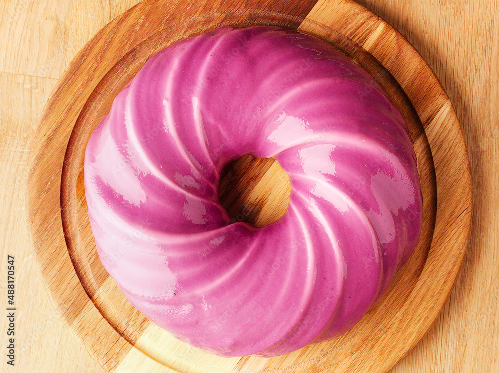 Very peri cake. Round cake with berry mousse in a mirror purple lilac pink  glaze. Wooden background. Restaurant menu and confectionery concept. Close  up. Copy space. March 8, Mother's Day, birthday. Stock