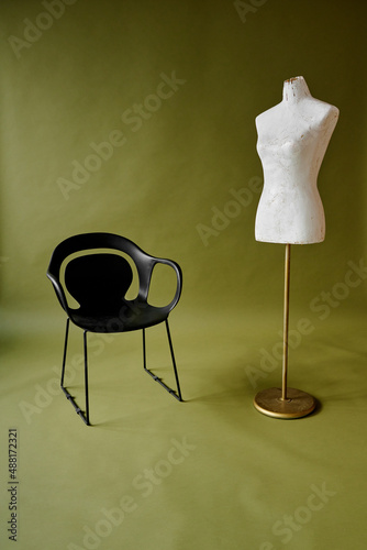 black chair and white mannequin on olive green background