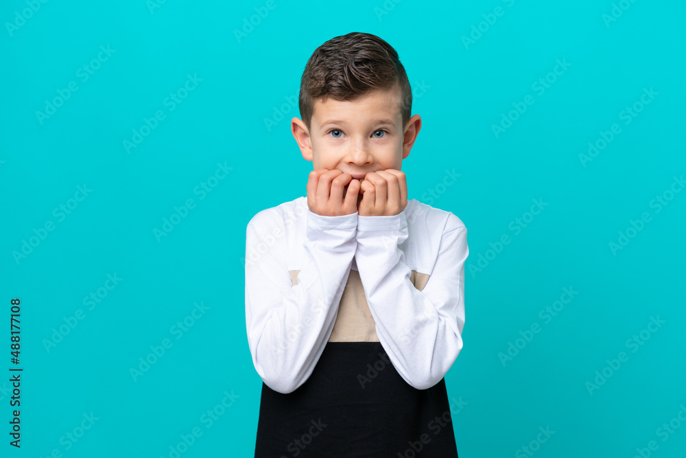 Little kid boy isolated on blue background nervous and scared putting hands to mouth Little kid boy isolated on blue background nervous and scared putting hands to mouth