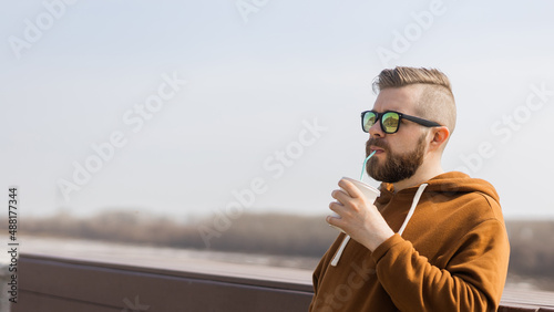 Stylish handsome hipster man holding drinks cocktail, spring time. Banner with copy space and place for advertising