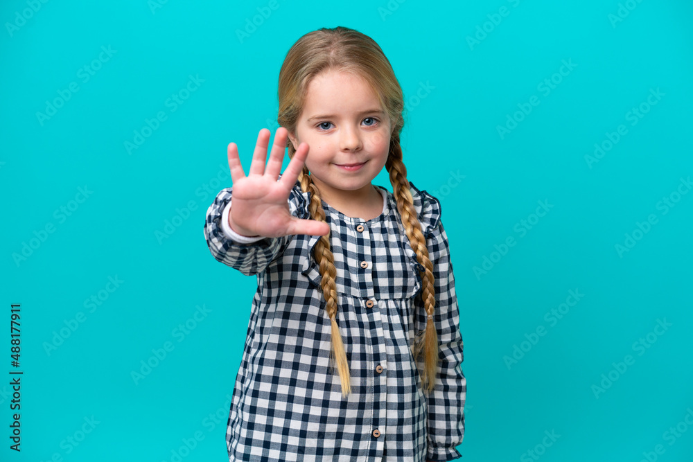 Little caucasian girl isolated on blue background saluting with hand with happy expression Little caucasian girl isolated on blue background saluting with hand with happy expression