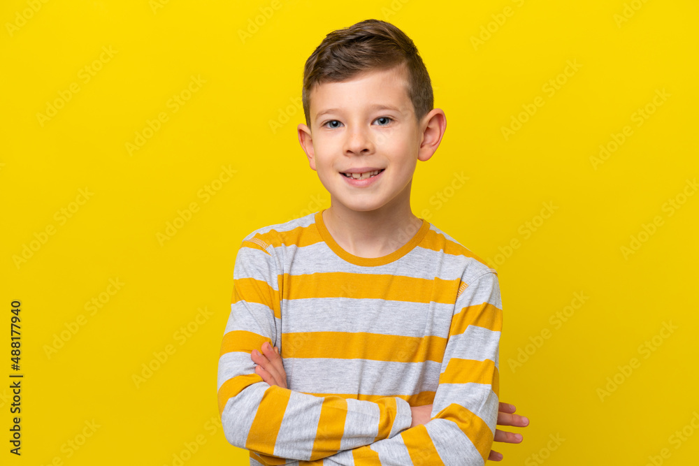 Little caucasian boy isolated on yellow background keeping the arms crossed in frontal position Little caucasian boy isolated on yellow background keeping the arms crossed in frontal position