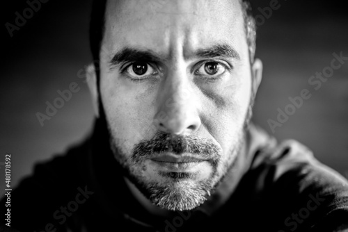 Black and white portrait of a middle aged men looking straight at the camera with a serious expression