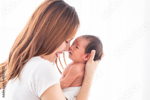 Beautiful Asian mother holding her baby in her arm and put her nose on baby's nose. Touching of love between mom and child concept, infant and mother concept.