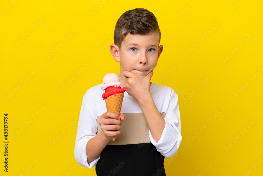 Little caucasian boy with a cornet ice cream isolated on yellow background having doubts and thinking Little caucasian boy with a cornet ice cream isolated on yellow background having doubts and thinking