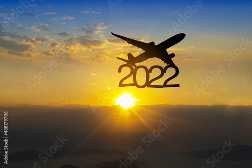 Silhouette airplane above  2022 text and beautiful sunset sky background,travelling and transportation in new year concept,copy space.