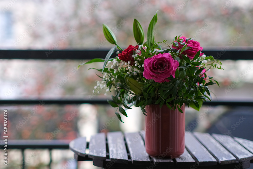 A beautiful bouquet of red and purple roses in a vase on a table outdoors