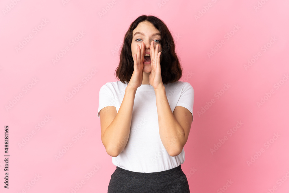 Teenager Ukrainian girl isolated on pink background shouting and announcing something Teenager Ukrainian girl isolated on pink background shouting and announcing something