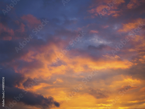 Cloudy sky at sunset. Dark purple-yellow natural background or wallpaper. The rays of the setting sun effectively illuminate the clouds. Beautiful and dramatic evening skies