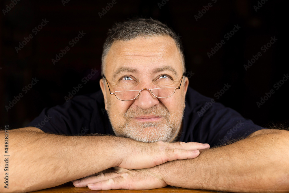 Obraz premium An adult man with a small stubble looks over his reading glasses, wrinkling his face.