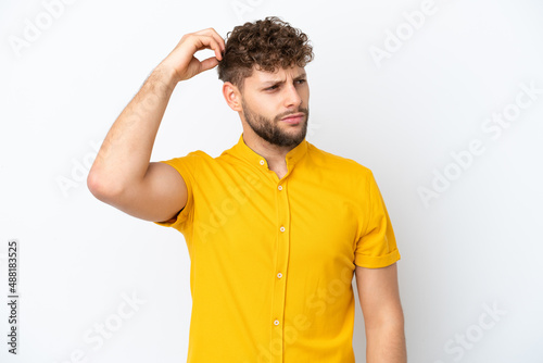 Young handsome caucasian man isolated on white background having doubts while scratching head