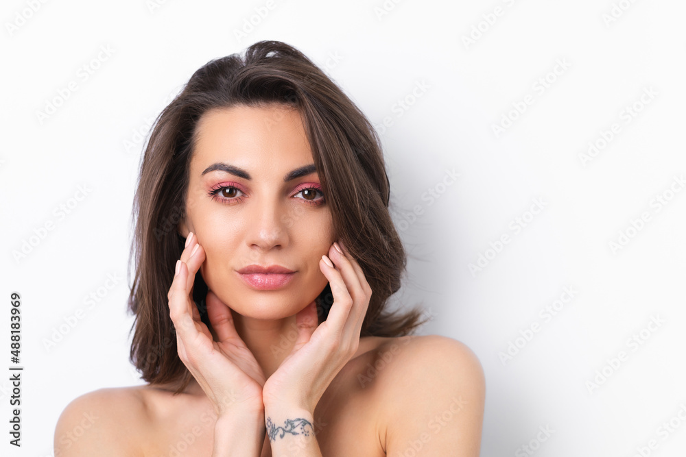 Young beautiful woman with perfect skin, bright spring pink make-up and naked shoulders on a white background.