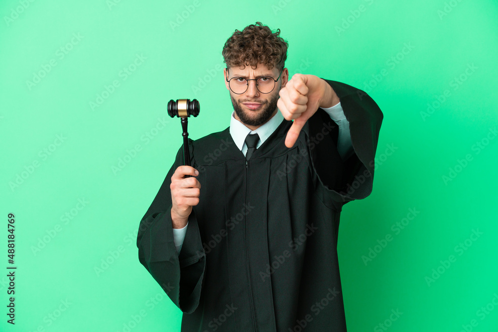 Naklejka premium Judge over isolated green background showing thumb down with negative expression