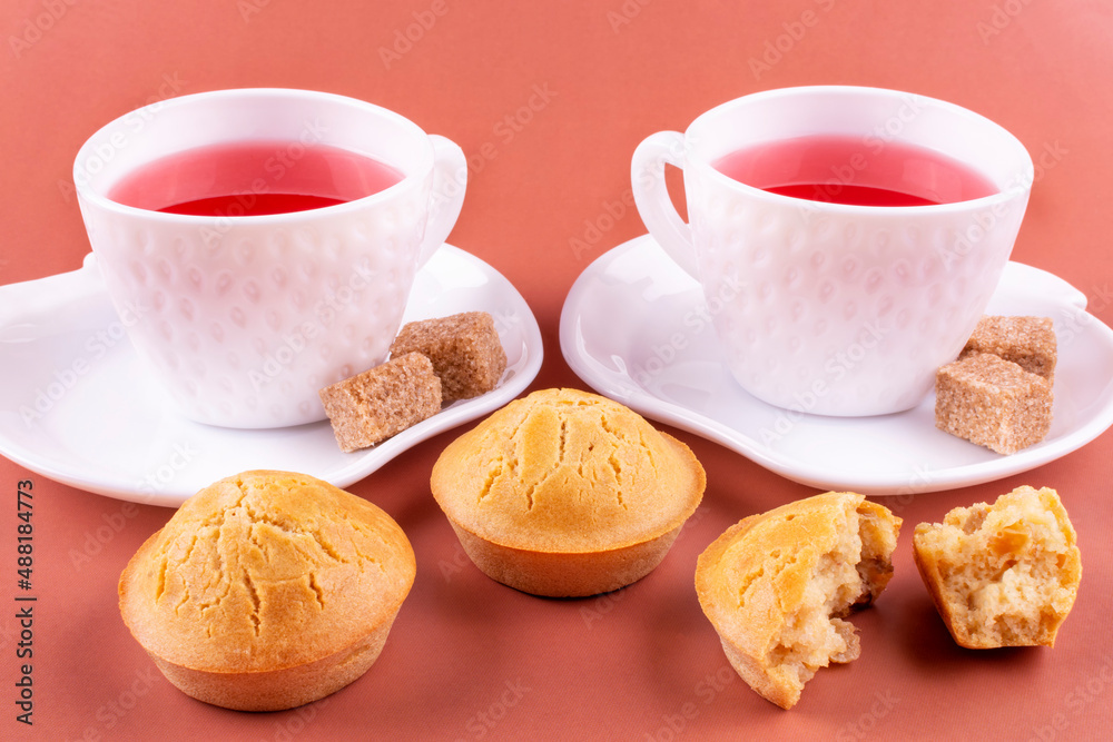 Homemade rice cupcakes with raisins on a white plate, two cups of raspberry tea, brown sugar on a pink background. Rice flour muffins. The concept of proper nutrition. Gluten-free breakfast. Homemade rice cupcakes with raisins on a white plate, two cups of raspberry tea, brown sugar on a pink background. Rice flour muffins. The concept of proper nutrition. Gluten-free breakfast.