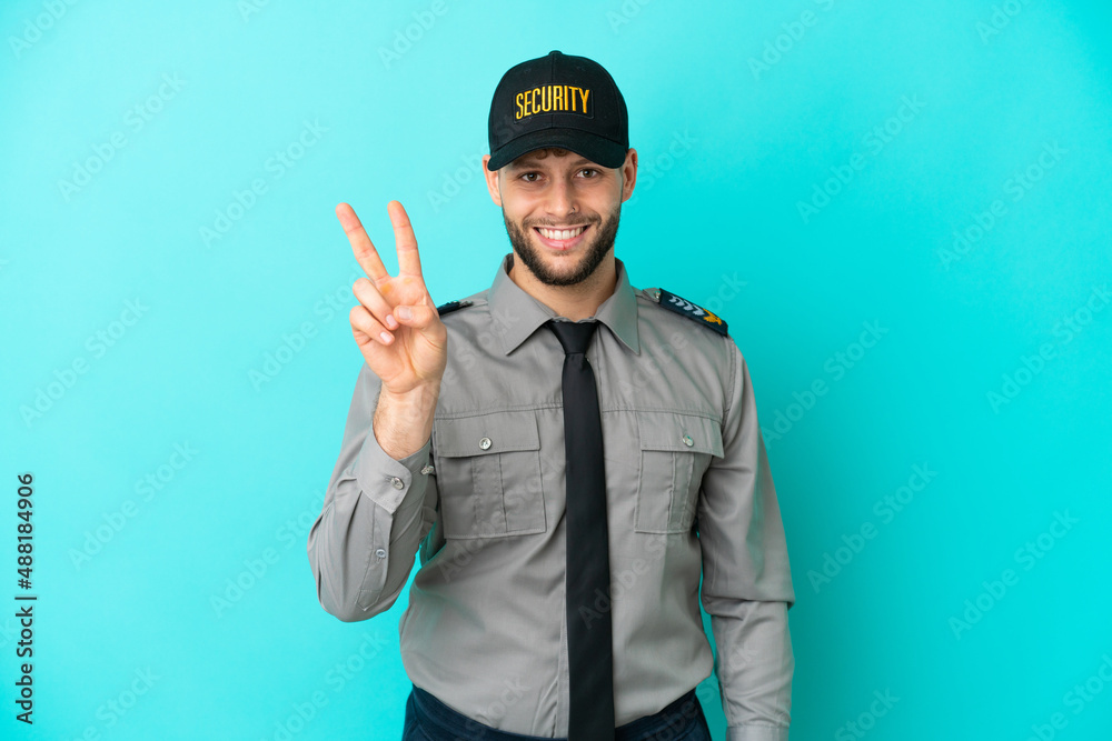 Young security man isolated on blue background smiling and showing victory sign Young security man isolated on blue background smiling and showing victory sign