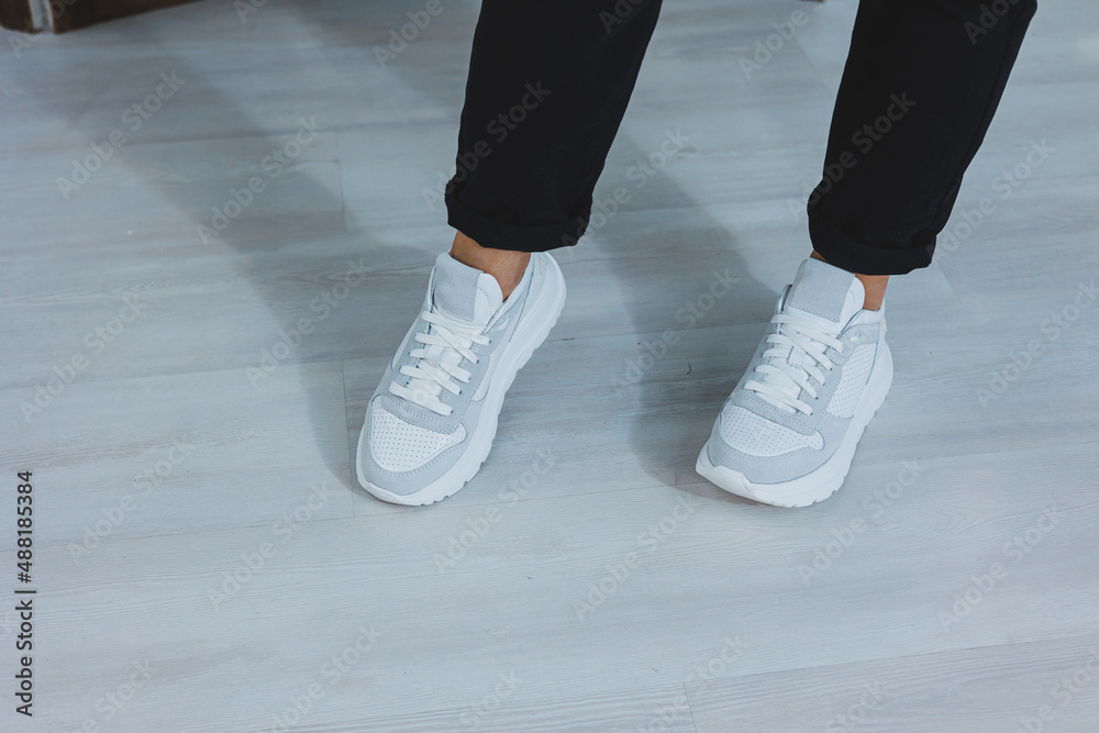 Beautiful women's shoes with legs, leather white sneakers, in the interior of a room or office, shoes for a woman, black trousers and white sneakers, casual and modern style, modern and trendy Beautiful women's shoes with legs, leather white sneakers, in the interior of a room or office, shoes for a woman, black trousers and white sneakers, casual and modern style, modern and trendy
