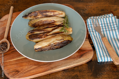 several endives braised in a dish on a wooden base