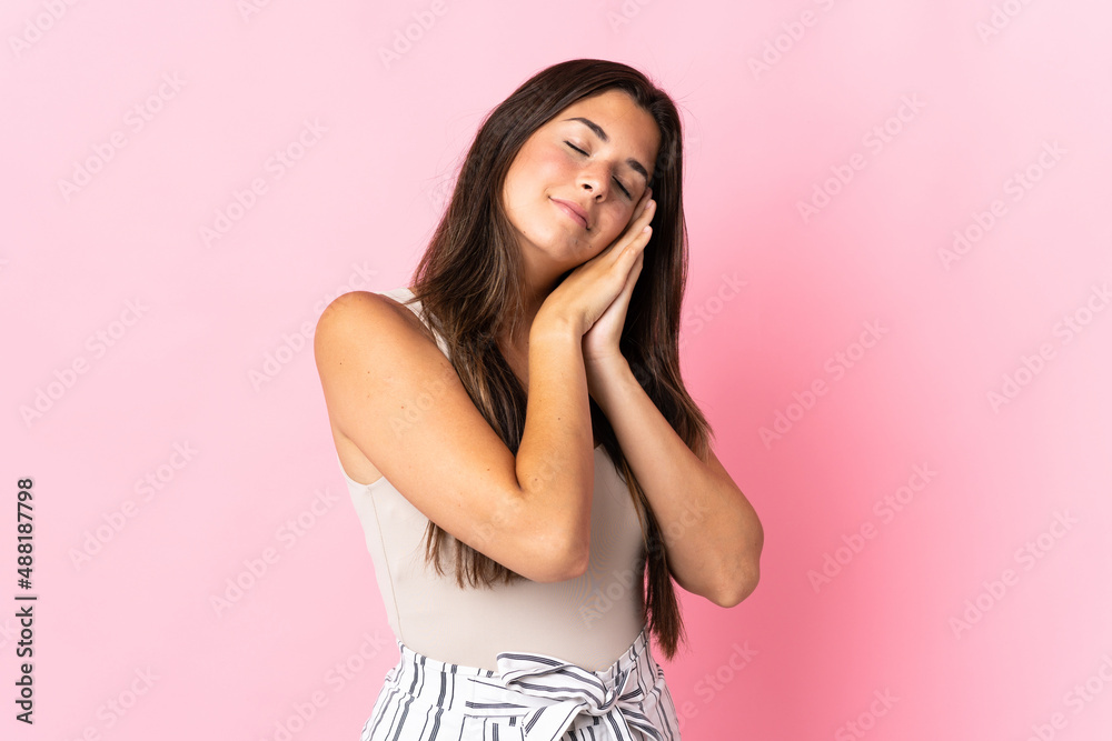 Young brazilian woman isolated on pink background making sleep gesture in dorable expression Young brazilian woman isolated on pink background making sleep gesture in dorable expression