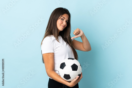 Young football player brazilian girl isolated on blue background proud and self-satisfied © luismolinero
