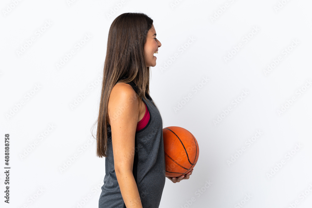 Young brazilian woman playing basketball isolated on white background laughing in lateral position