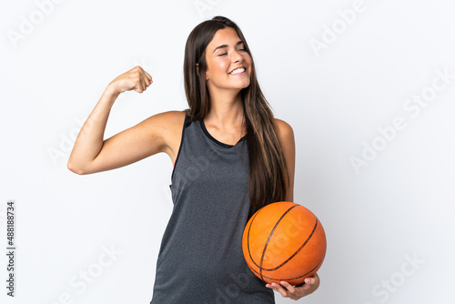 Young brazilian woman playing basketball isolated on white background doing strong gesture © luismolinero