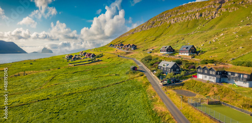 Sunny summer view from flying droneof Kirkjubour village with Hestur Island on background. Panoramic morning scene of Faroe Islands, Denmark, Europe.  Beauty of nature concept background. photo