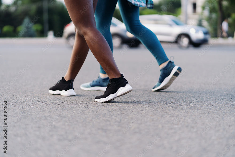 Side view of friends legs in sportswear jogging in the city. Multiethnic women having a fitness workout.