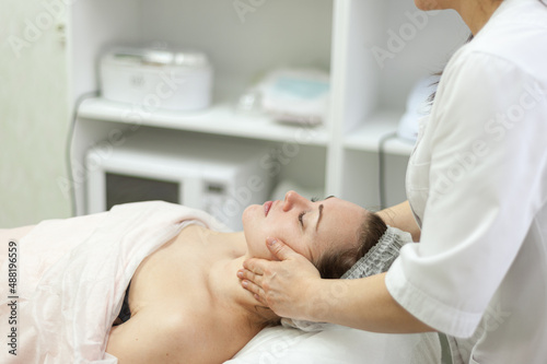 Facial massage. The cosmetologist makes a facial massage for an attractive brunette woman. Professional care of the skin and muscles of the face. rejuvenating beauty treatments.