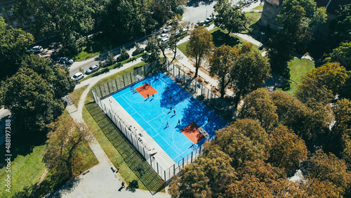 Aerial view of the blue stadium in the park, teenagers playing basketball