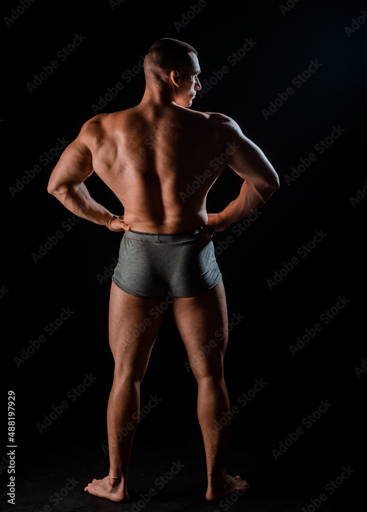 Portrait of strong man showing muscles isolated on black