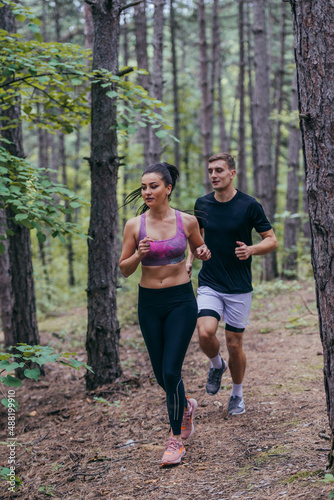 Fit male and female athletes running in nature. Nature and sports concept.