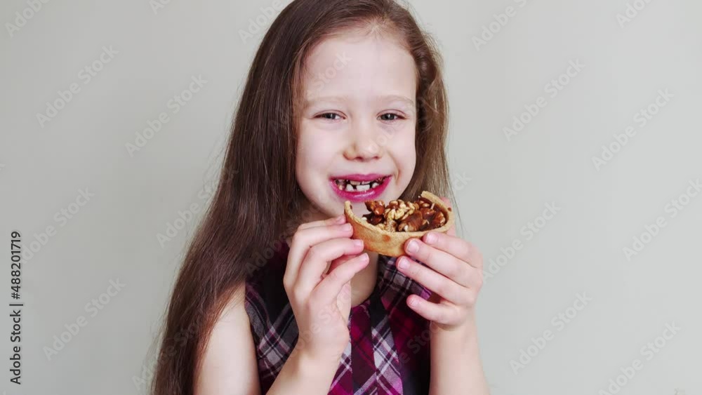 Little girl eats cake with walnuts and caramel. Kid is enjoying a sweet cake. Little girl eats cake with walnuts and caramel. Kid is enjoying a sweet cake.