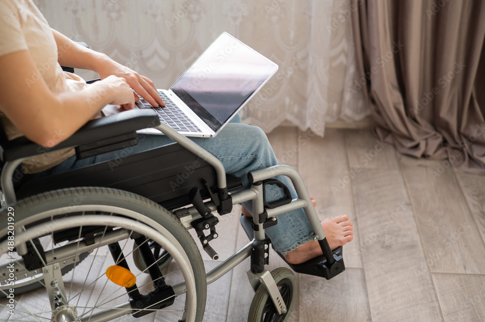 Obraz premium A woman in a wheelchair uses a laptop.