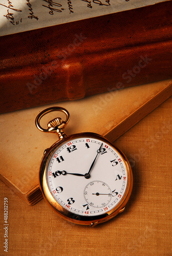 old pocket watch on background of old books. Concept of the passage of time and history, nostalgia, old age. Retro style with space for text
