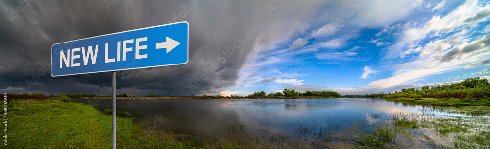New Life sign on background of amazing landscape nature before thunder storm. Dark clouds cover blue sky at wild river. Incredible weather panorama